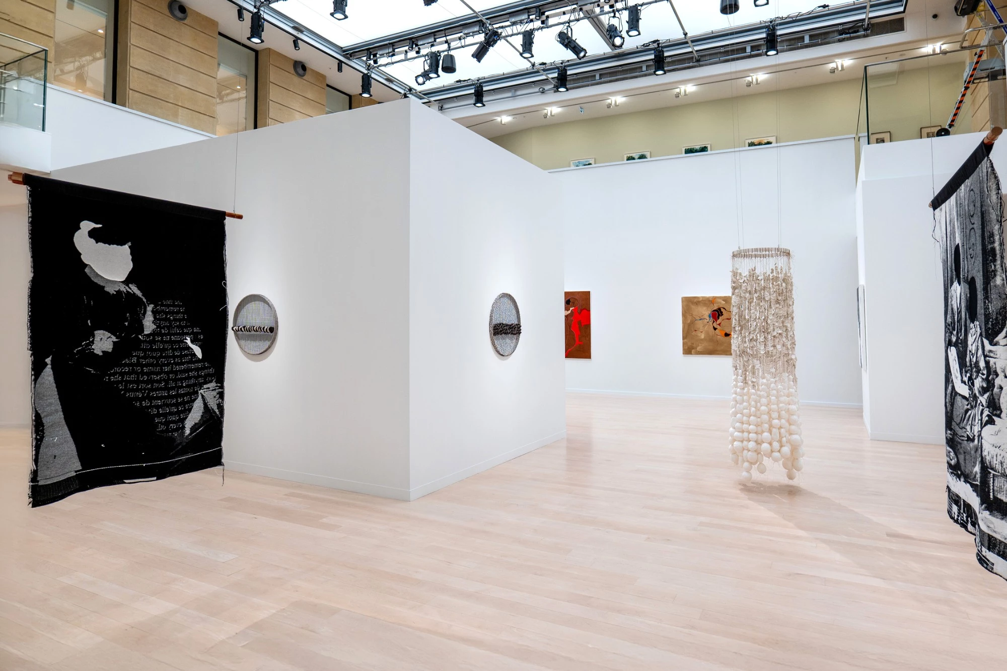 Exposition au Centre culturel canadien à Paris : blocs de cloisons Mila-wall blancs autoportants sous une verrière, devant des œuvres textiles suspendues et une sculpture