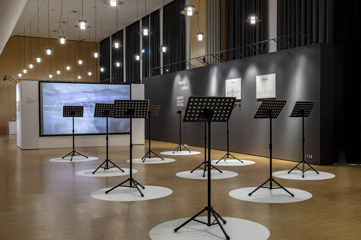 Exposition « Musik aufs Auge » à la Bibliothèque régionale du Wurtemberg, Stuttgart : pupitres sur des cercles blancs devant une cloison Mila-wall sombre