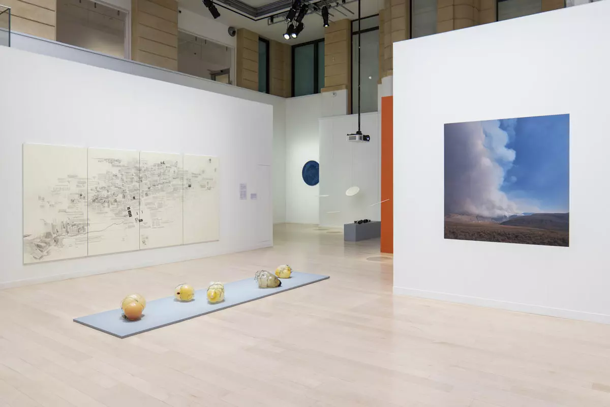 Cloisons Mila-wall blanches avec dessin et photographie au Centre culturel canadien à Paris, devant des objets posés sur un podium bas